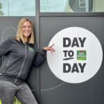 femme souriante avec l'enseigne day to day by louis delhaize