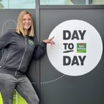 femme souriante avec l'enseigne day to day by louis delhaize